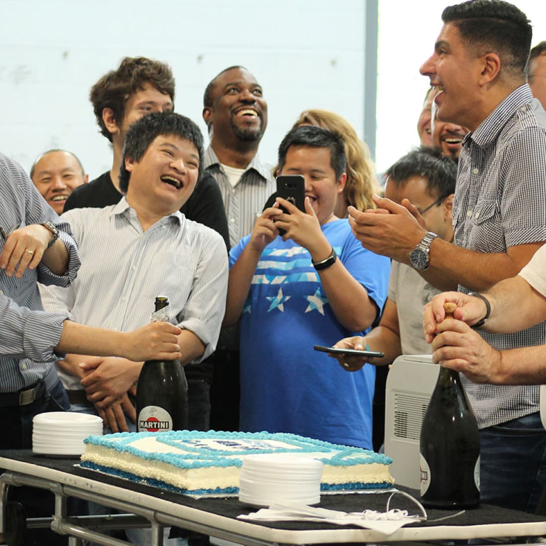 Group shot of smiling and laughing Asigra employees cutting a cake at the grand opening of the new office..